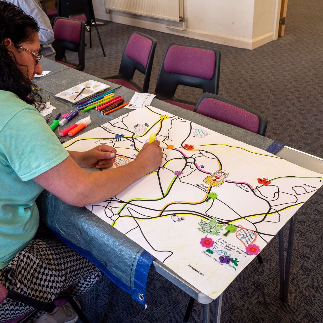 Child drawing colourful lines on a large white paper